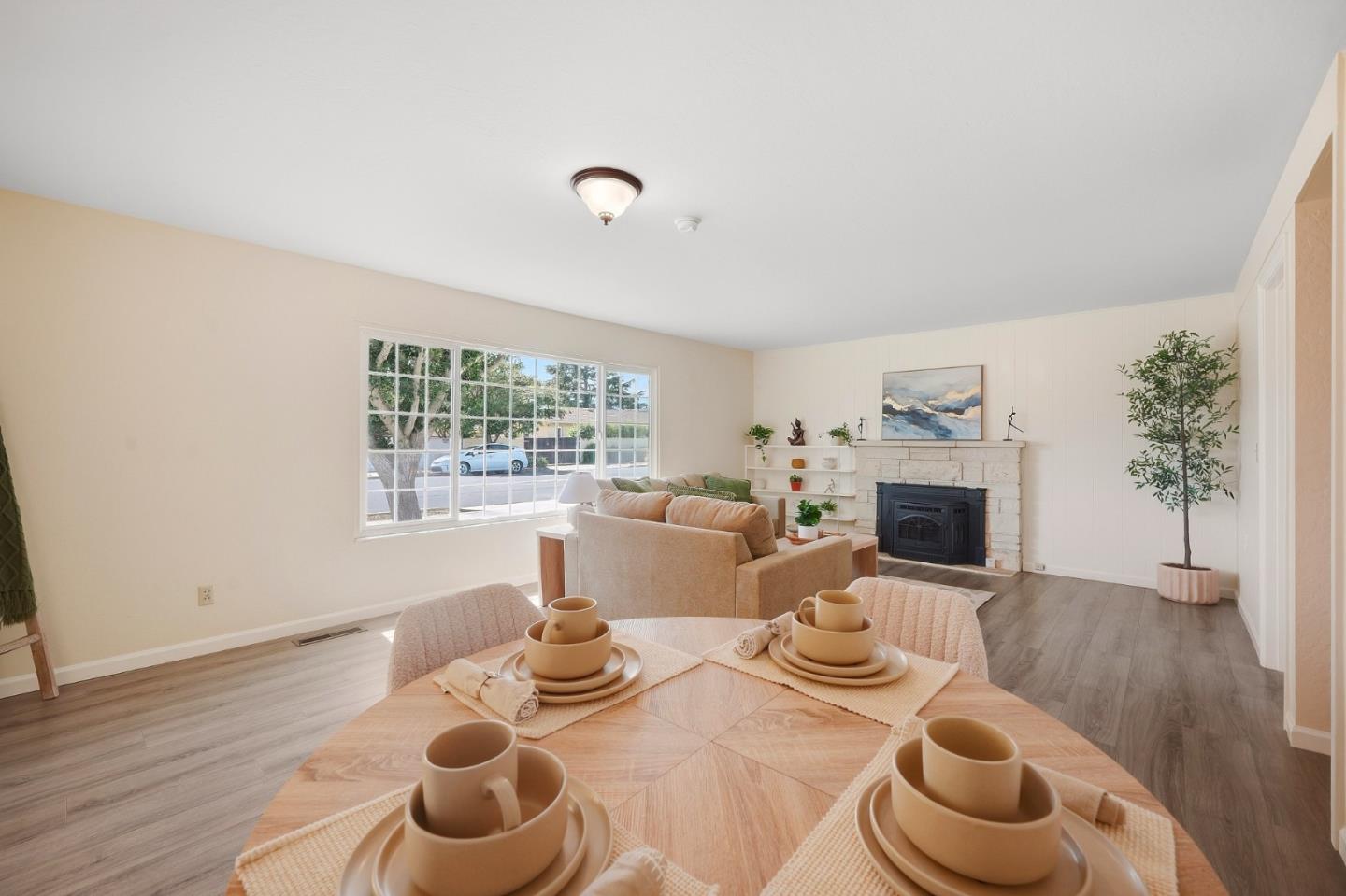 Staged living and dining area with a stone fireplace and large front window.