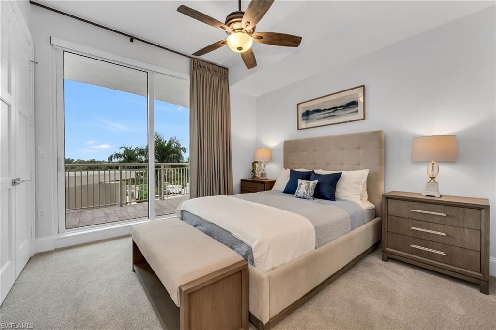 Furnished bedroom with a king bed and sliding glass doors opening onto a palm-lined balcony.