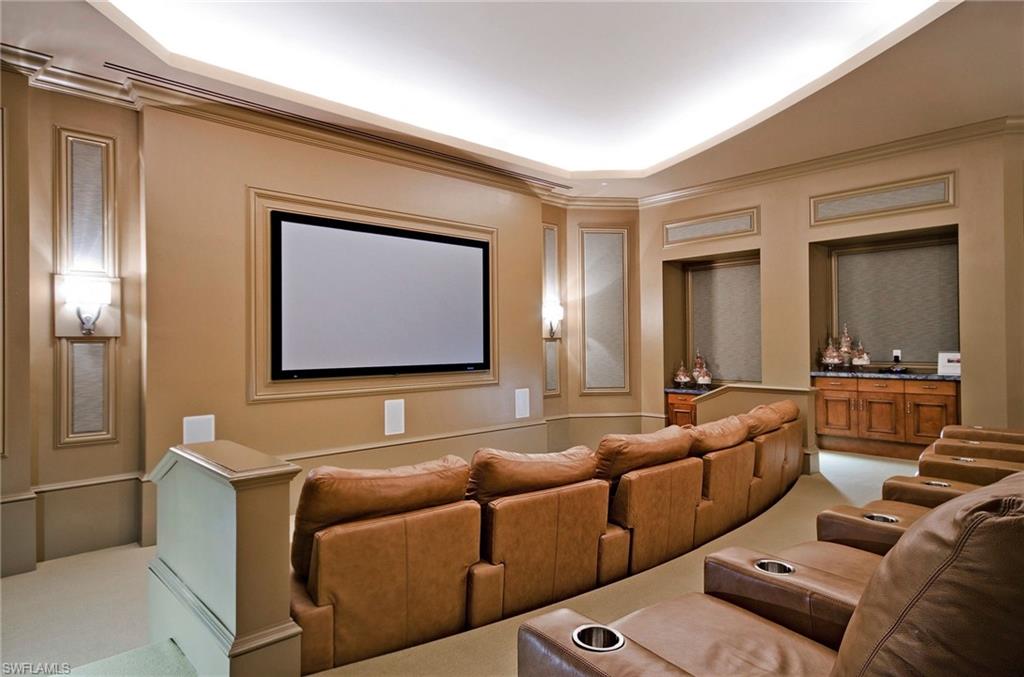 Screening room with rows of brown leather recliners facing a large wall-mounted screen.