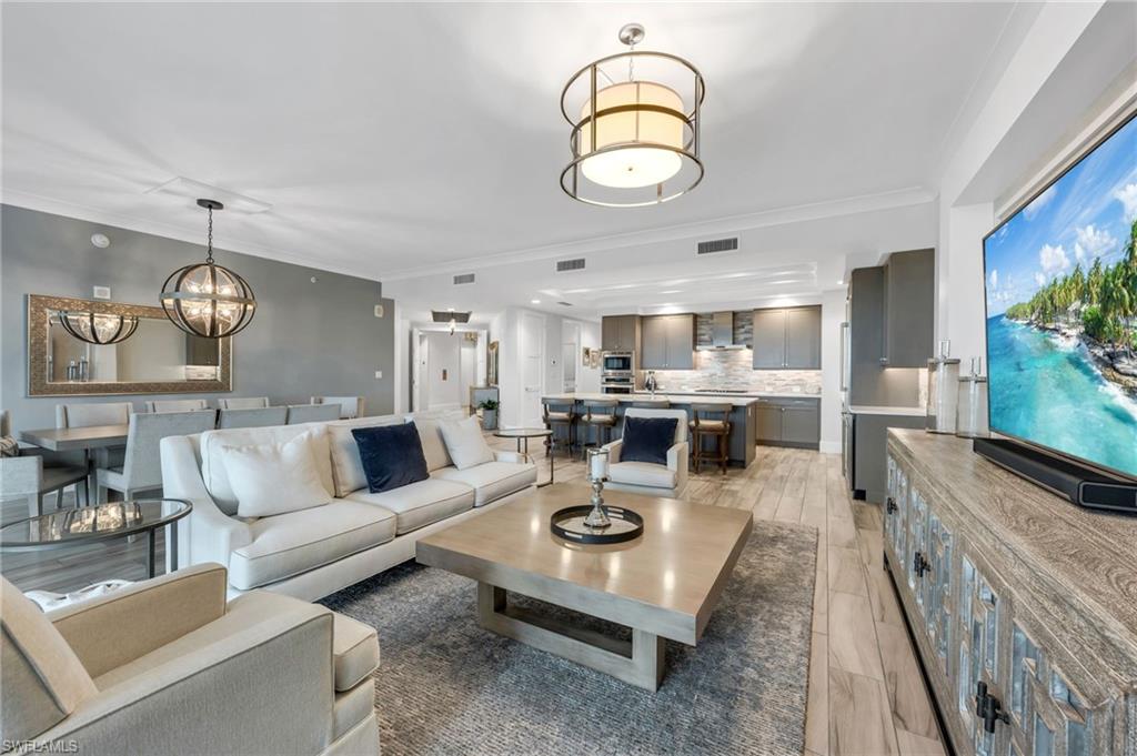 Open-plan living room with a white sectional, dining area, and gray kitchen.