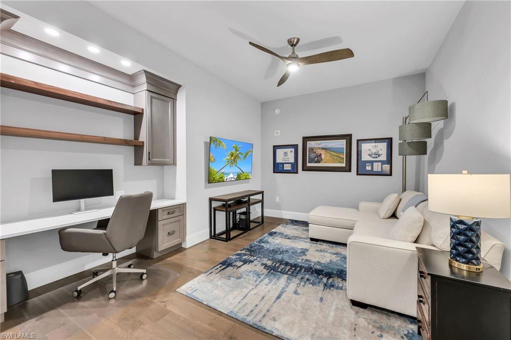 Home office and sitting area with a built-in desk, gray chair, white sectional, and blue patterned rug.