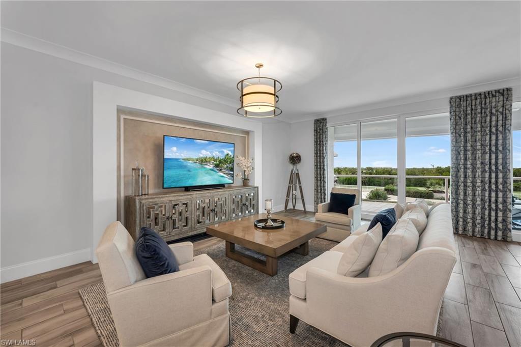 Living room with cream seating, a carved media cabinet, and sliding doors to a green-view balcony.