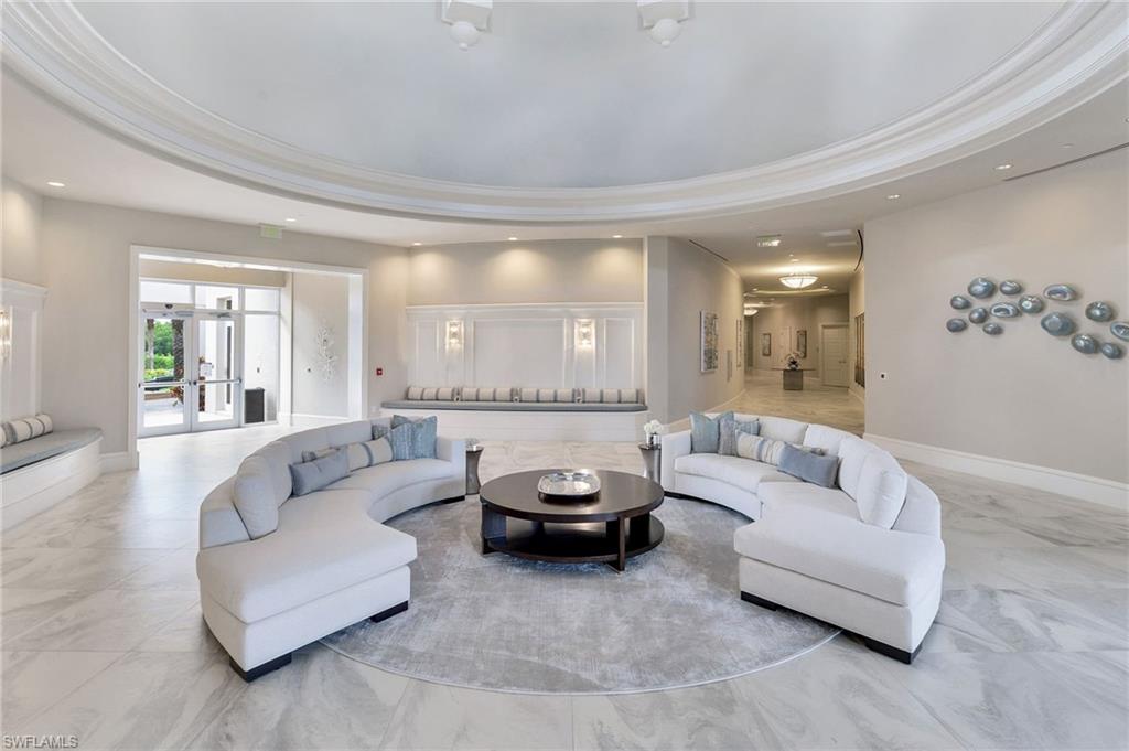 Condominium lobby with curved white sofas around a coffee table beneath a sweeping recessed ceiling.
