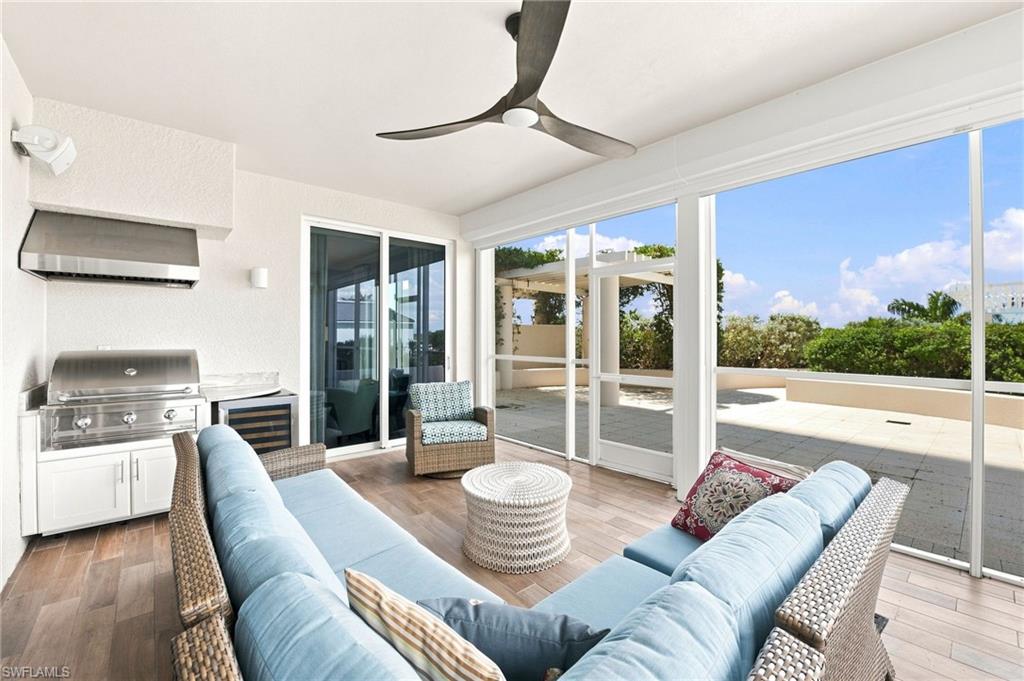 Furnished condo lanai with a built-in grill, ceiling fan, wicker seating, and an open terrace.