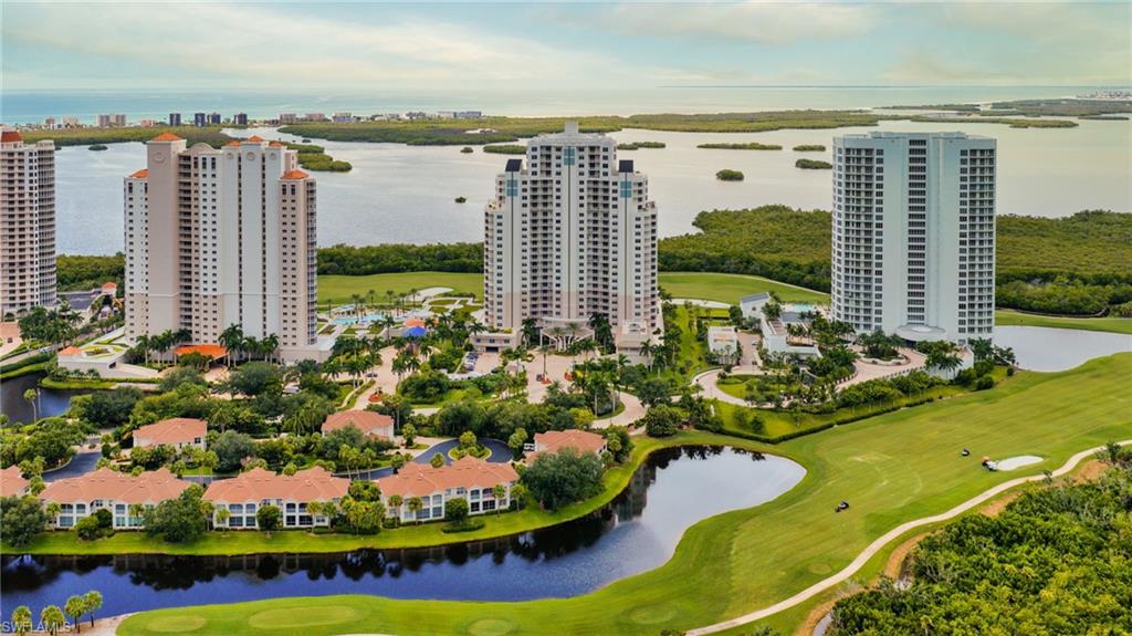 Aerial view of Bonita Bay towers beside a golf course, waterways, and coastal wetlands.