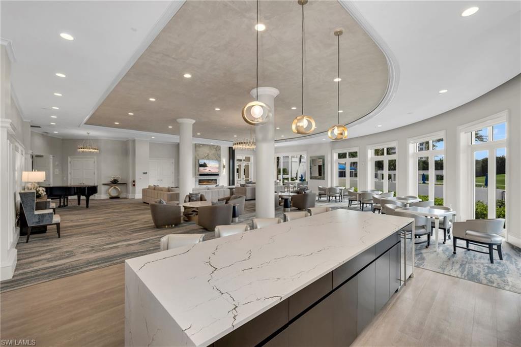 Furnished lounge and dining area with a large marble-topped island and rows of windows.