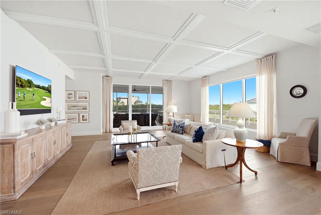 Bright living room with a coffered ceiling, cream seating, and large windows.