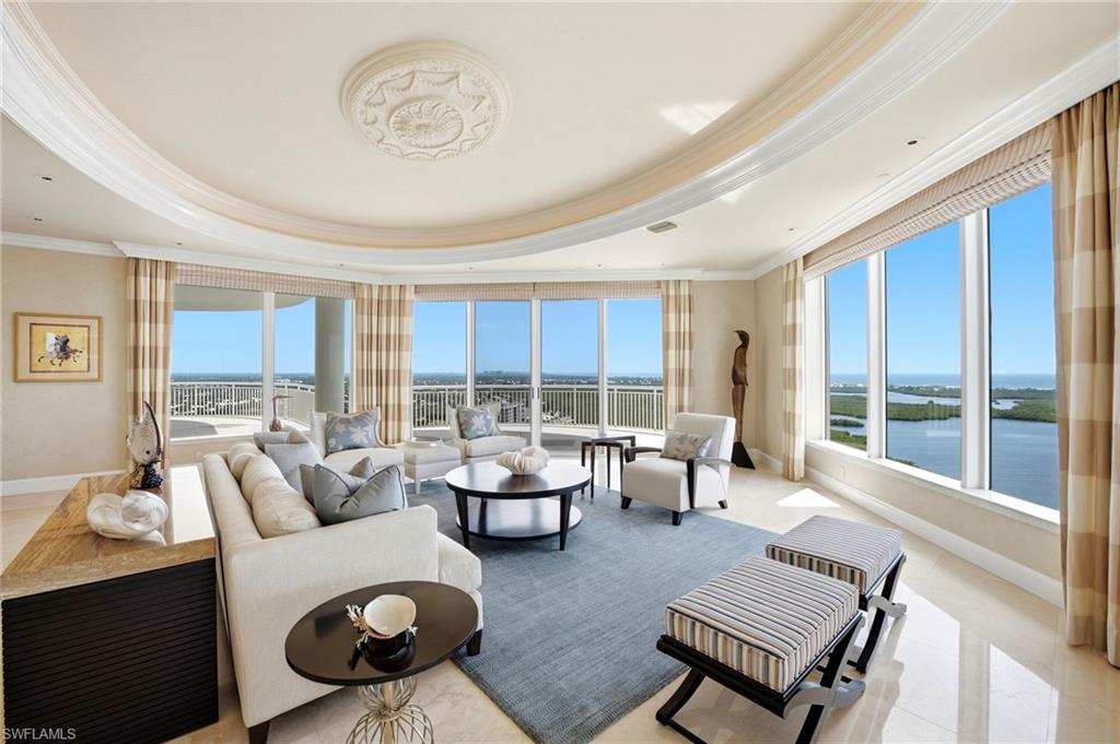 Living room with floor-to-ceiling windows overlooking waterways and greenery.