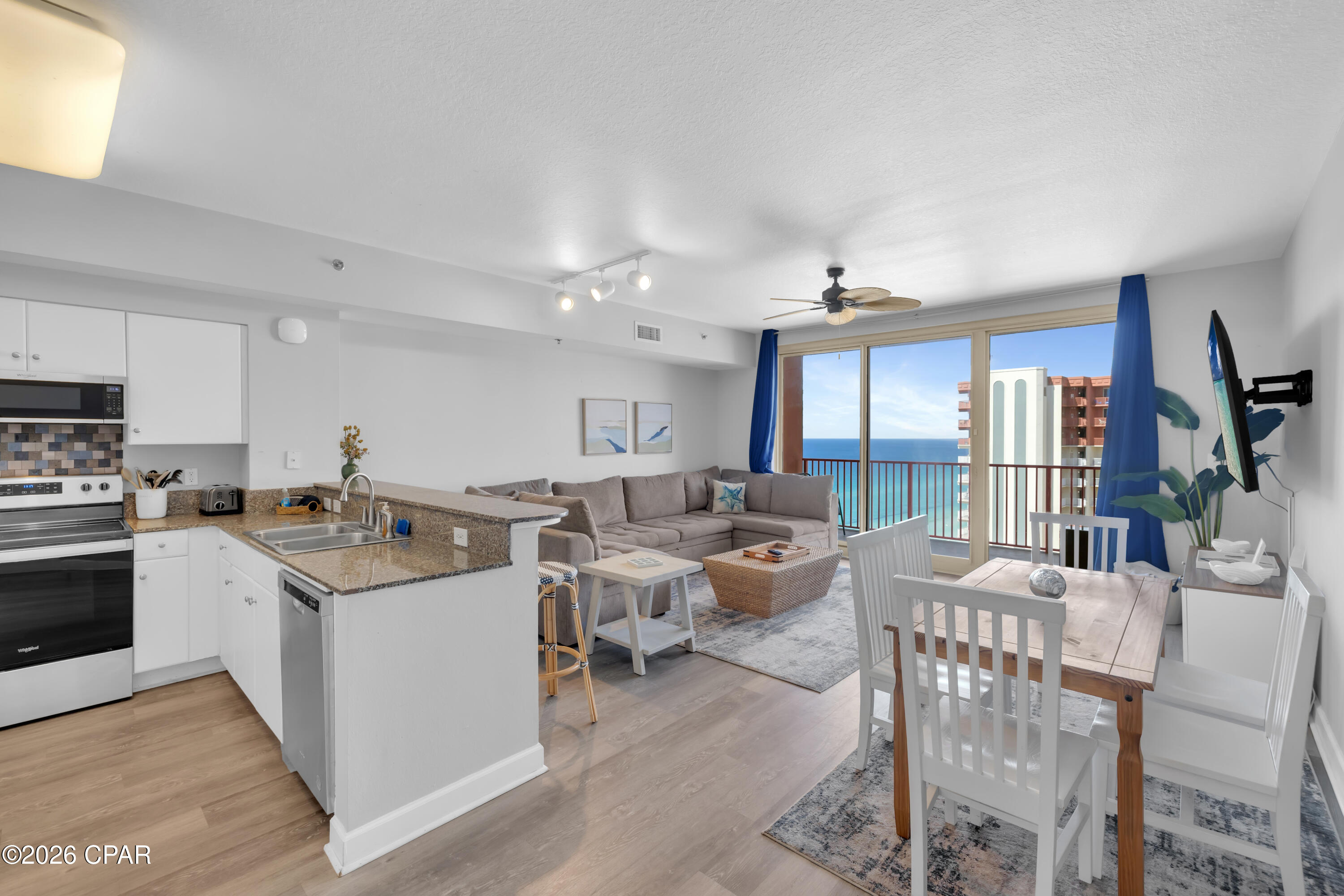 Open-plan condo kitchen, living, and dining area with ocean views from the balcony.