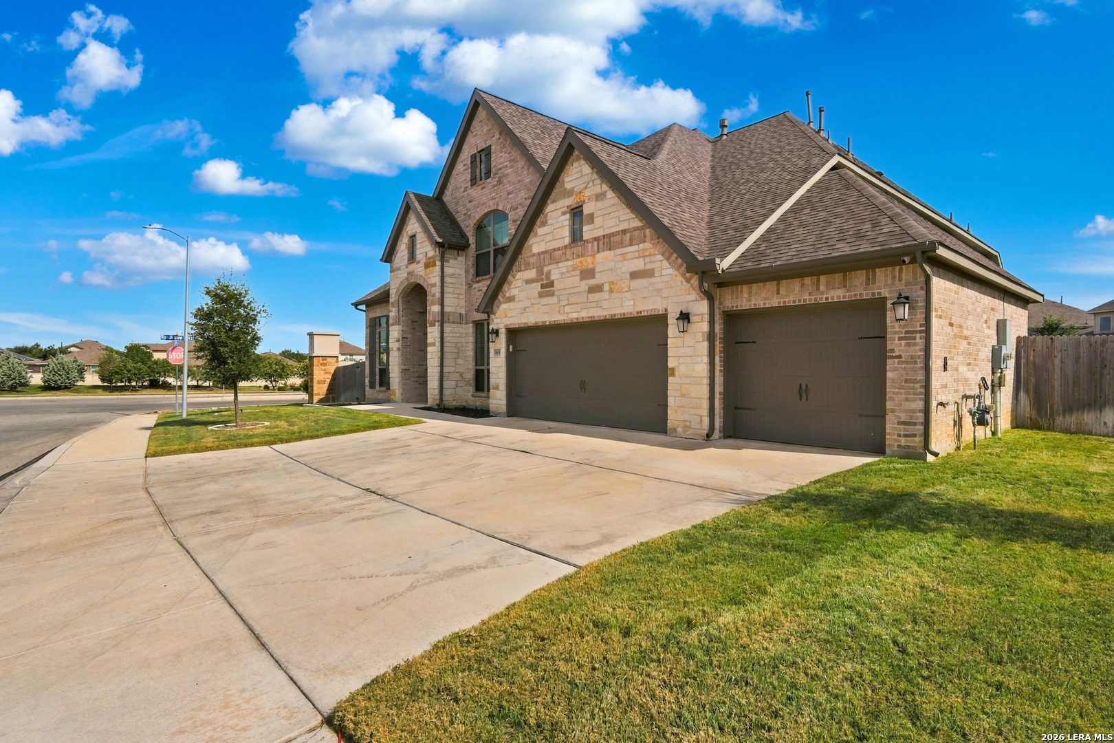 Two-story stone-and-brick house with a three-car garage and wide driveway.