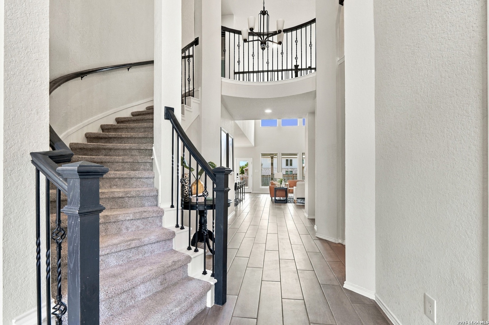 Two-story entryway with a curved staircase, wrought-iron railings, and a tiled hallway.