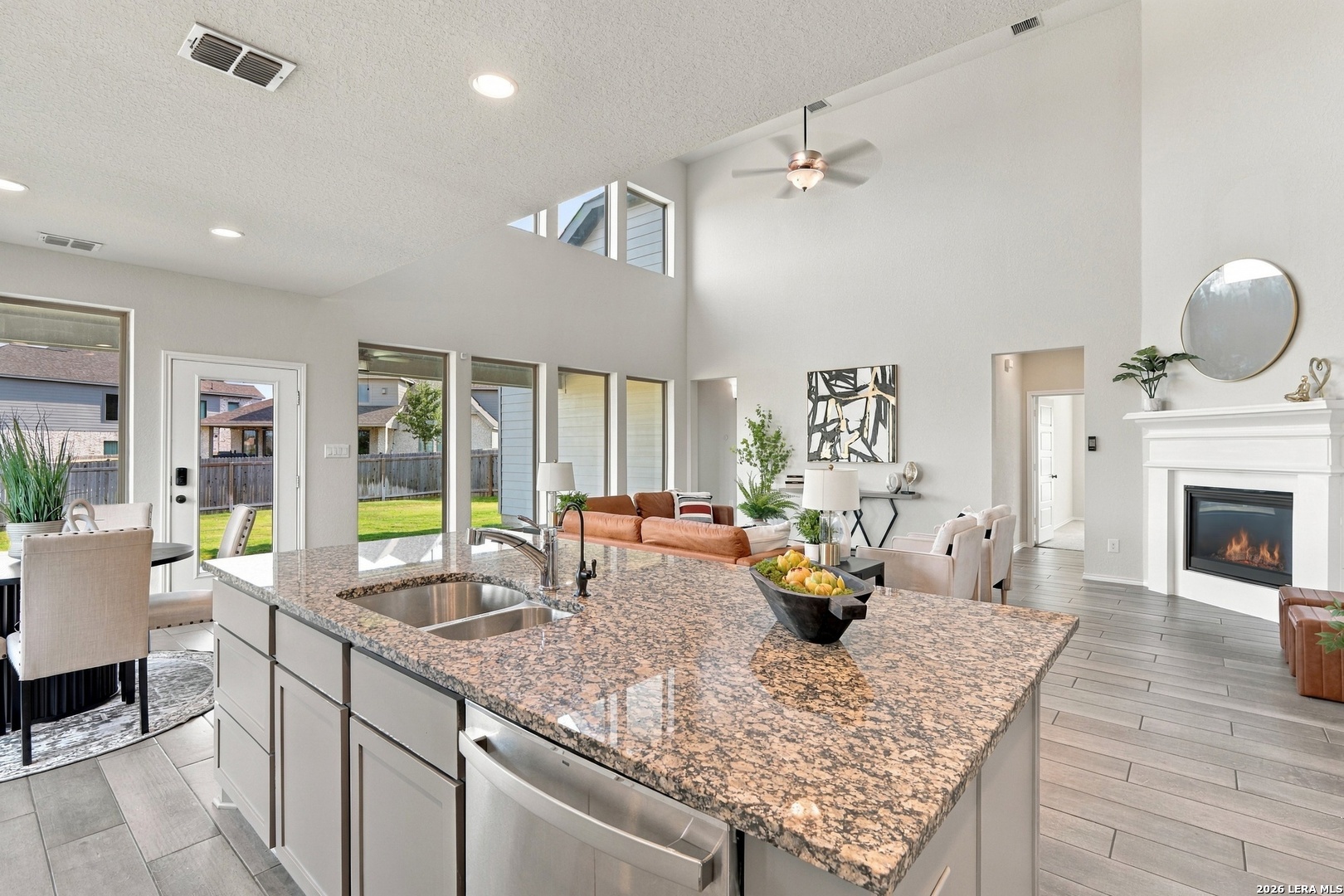 Open-plan kitchen with a large granite island, double-basin sink and view of the living room fireplace.