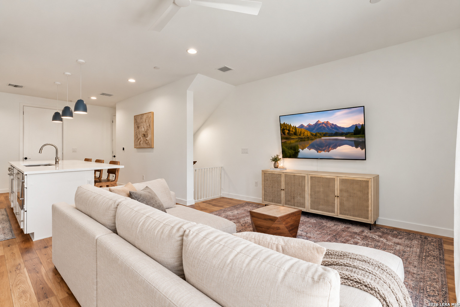Open-plan living room with a white sofa, patterned rug, and adjoining kitchen island.