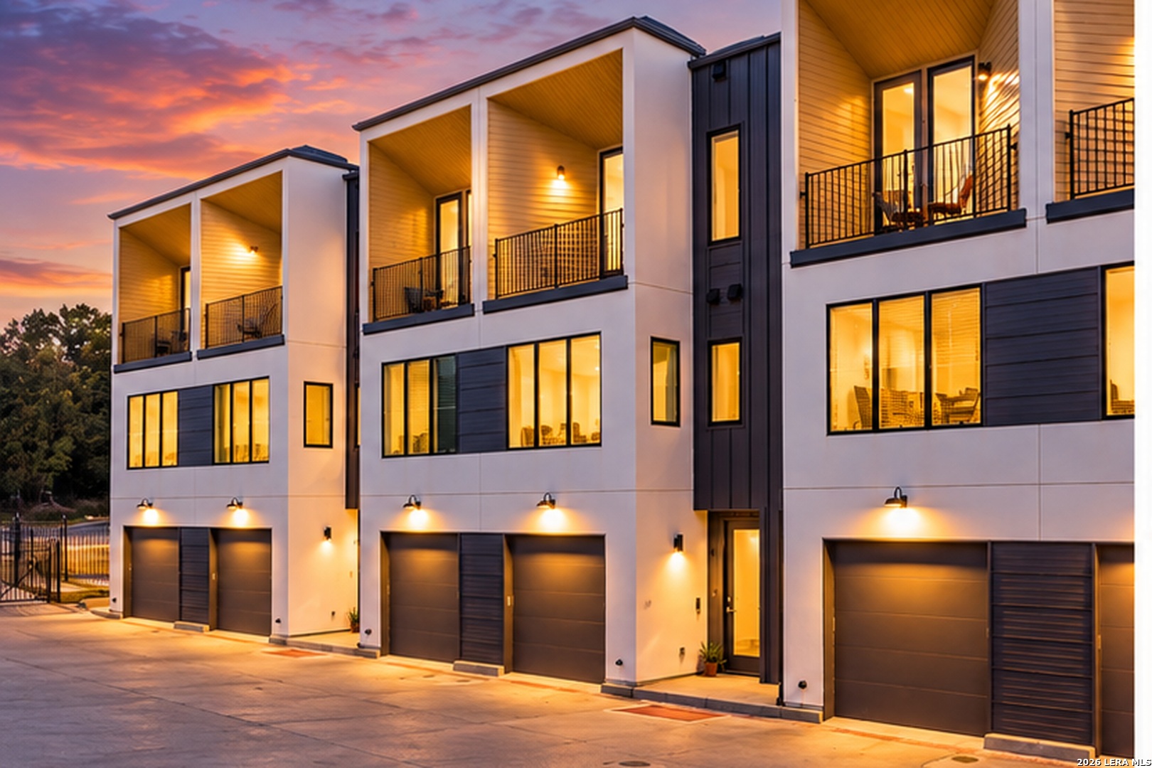 Modern townhomes with private balconies and garages beneath a vivid dusk sky.