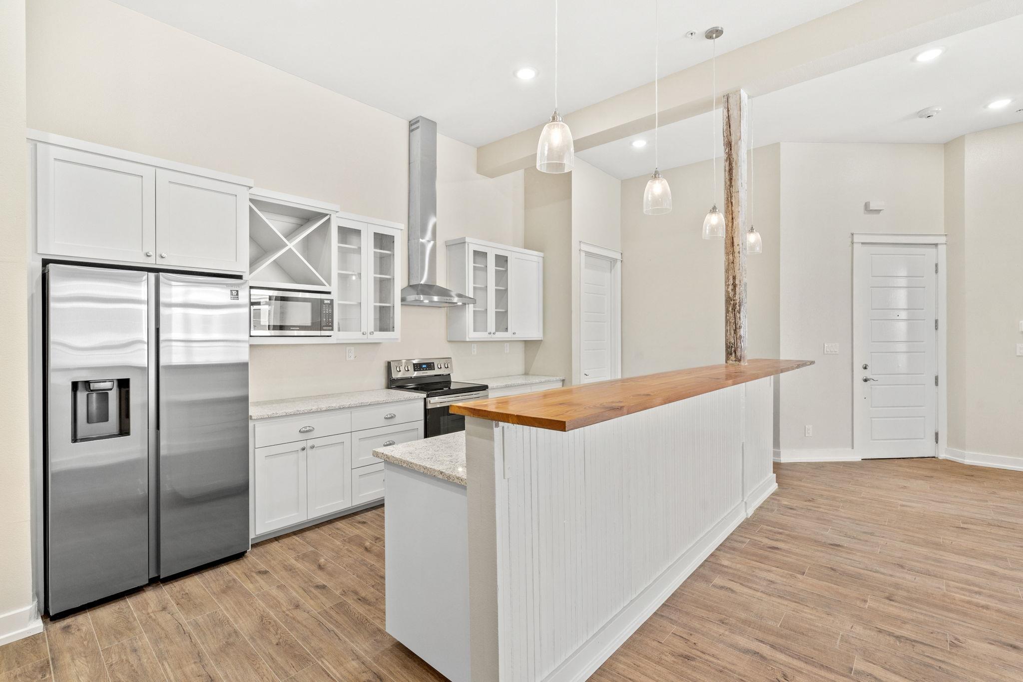 Kitchen with white cabinetry, stainless steel appliances, and a long wood-topped island.