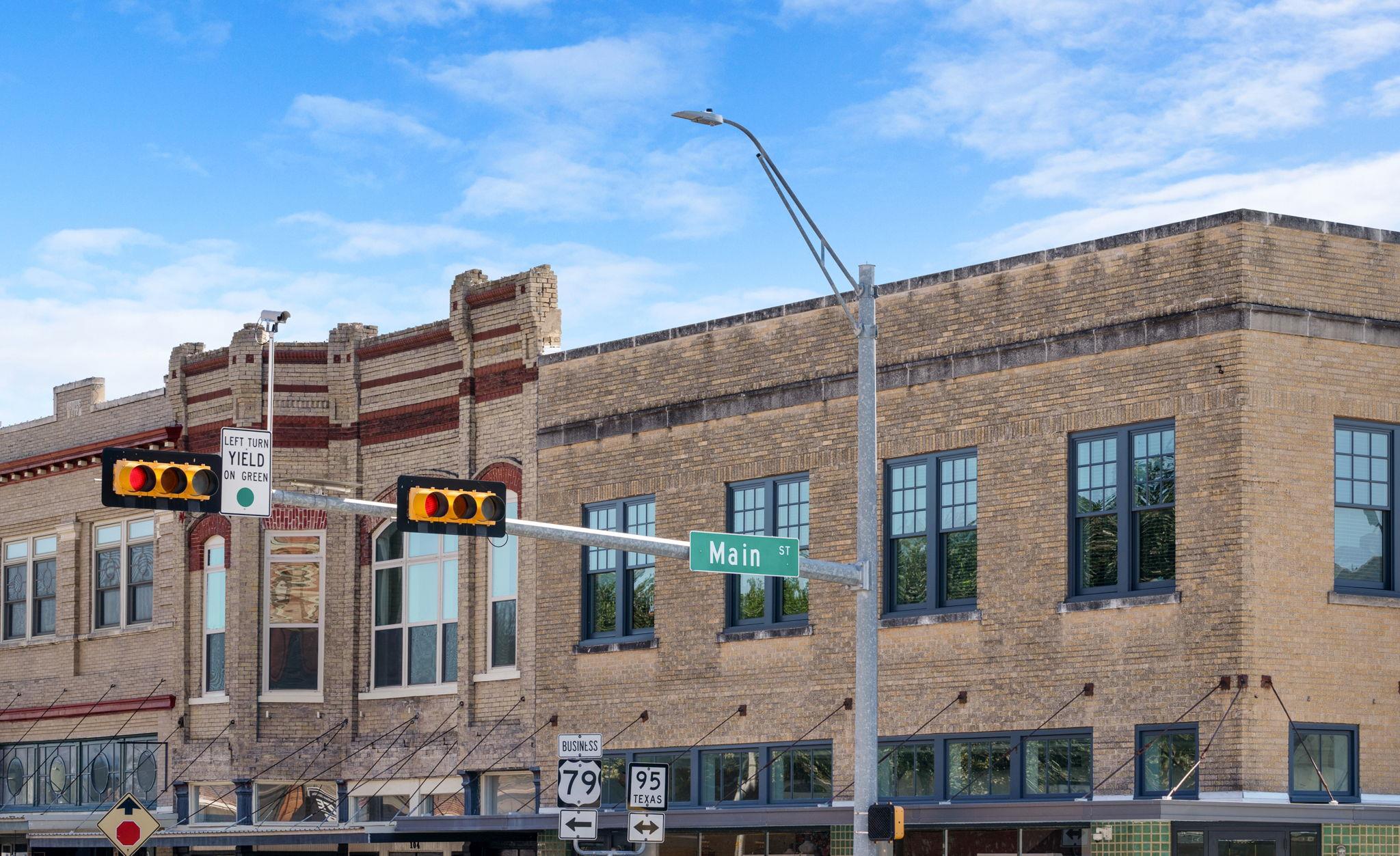 Two-story brick commercial building on a downtown corner, beneath Main Street traffic signals.