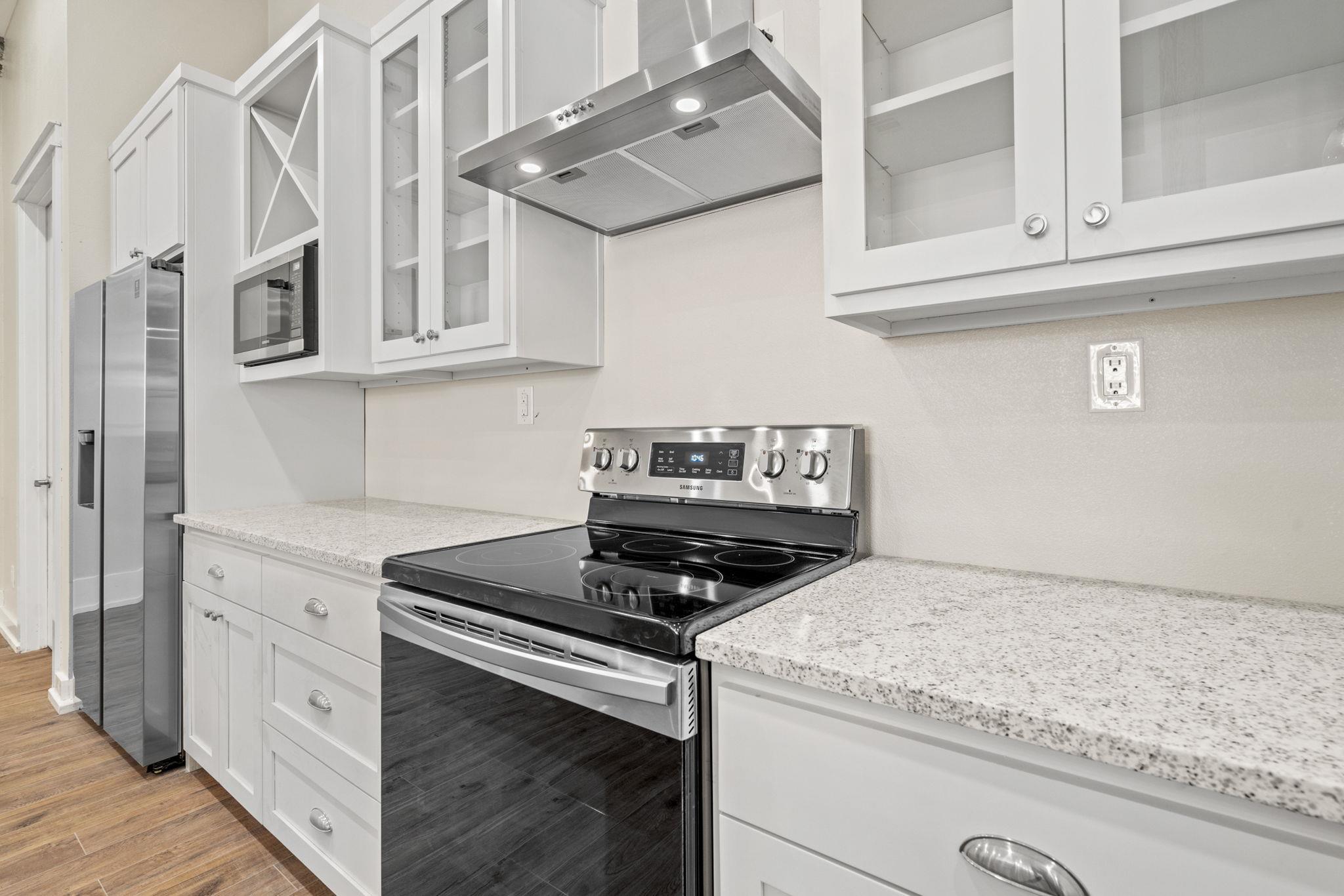 Modern kitchen with white cabinetry, speckled countertops, and stainless steel appliances.