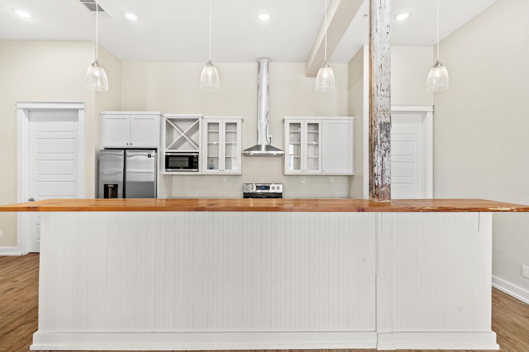 Kitchen with white cabinetry, stainless steel appliances, and a long wood-topped island.