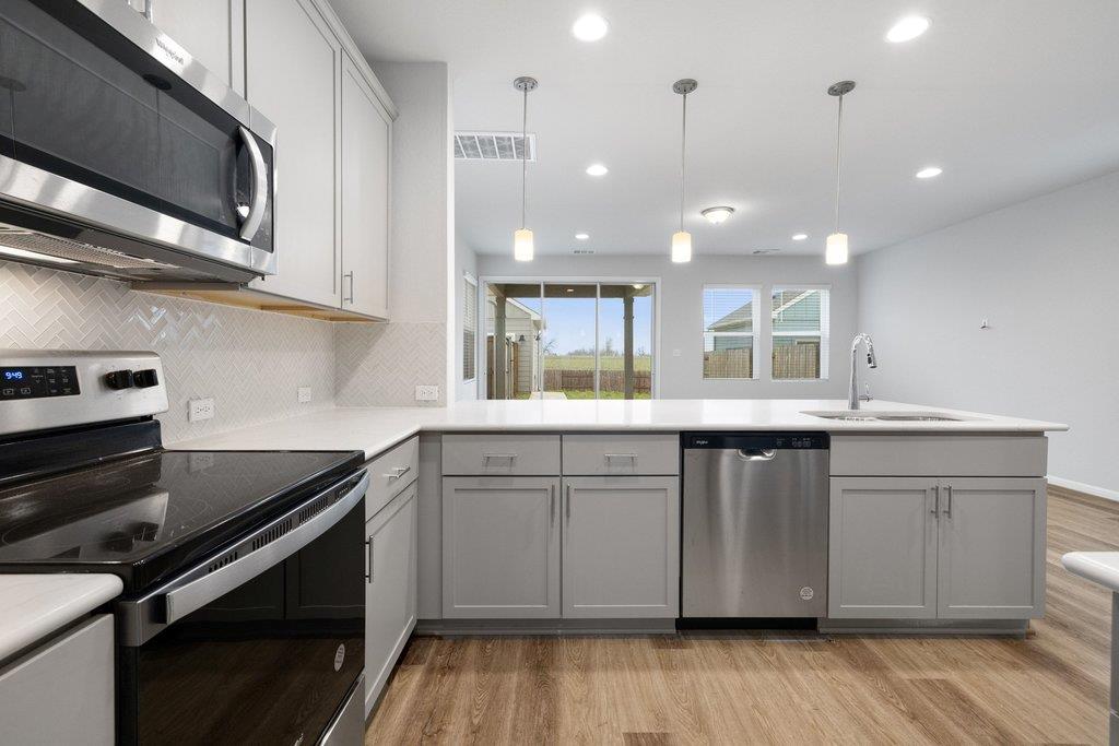 Modern kitchen with gray cabinets, stainless steel appliances, and sliding glass doors to the yard.