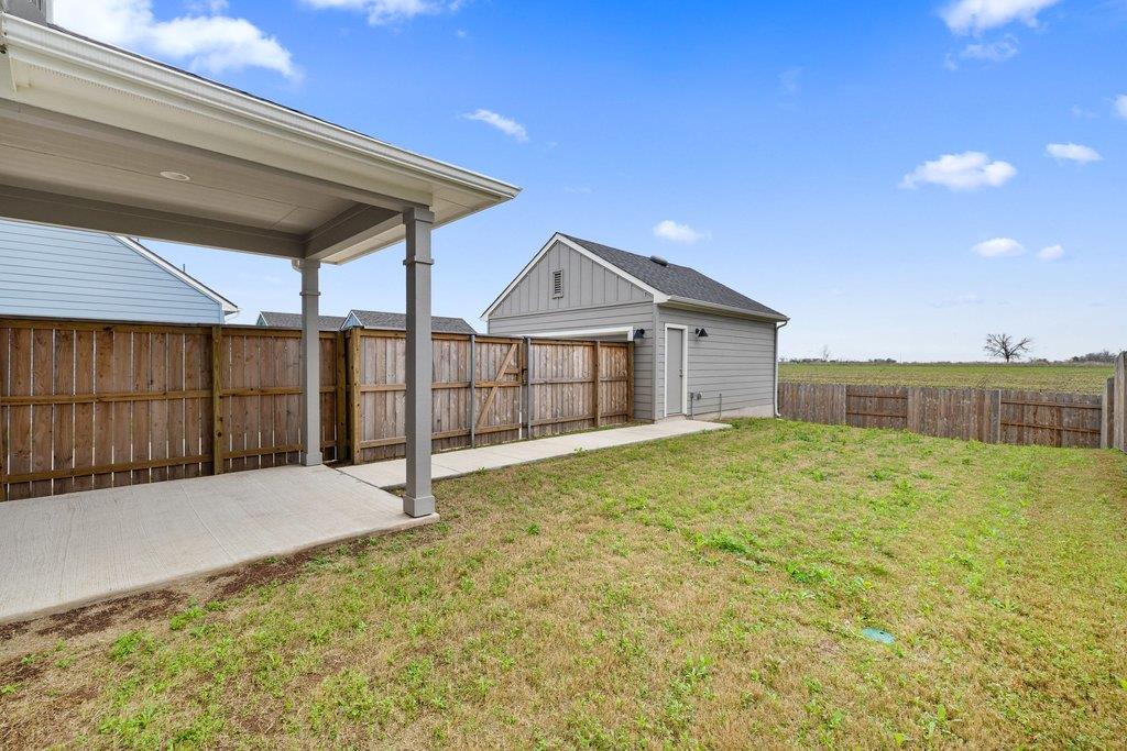 Fenced backyard with a covered patio, detached storage shed, and grassy lawn.