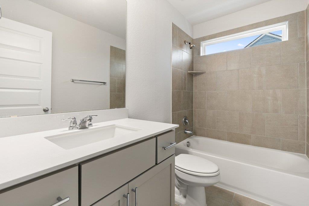Bathroom with a tiled tub surround, white vanity, and high horizontal window.