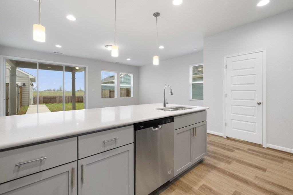 Unfurnished kitchen with a large island, stainless-steel dishwasher, and sliding glass doors to the backyard.