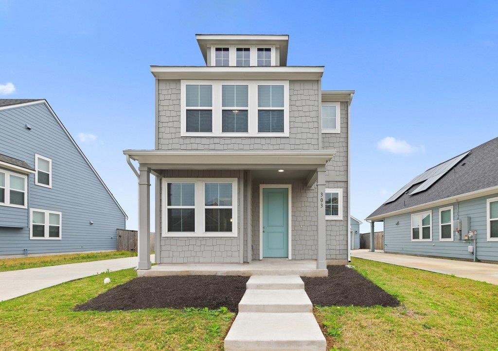 Two-story gray house with a covered porch, turquoise door, and concrete walkway.