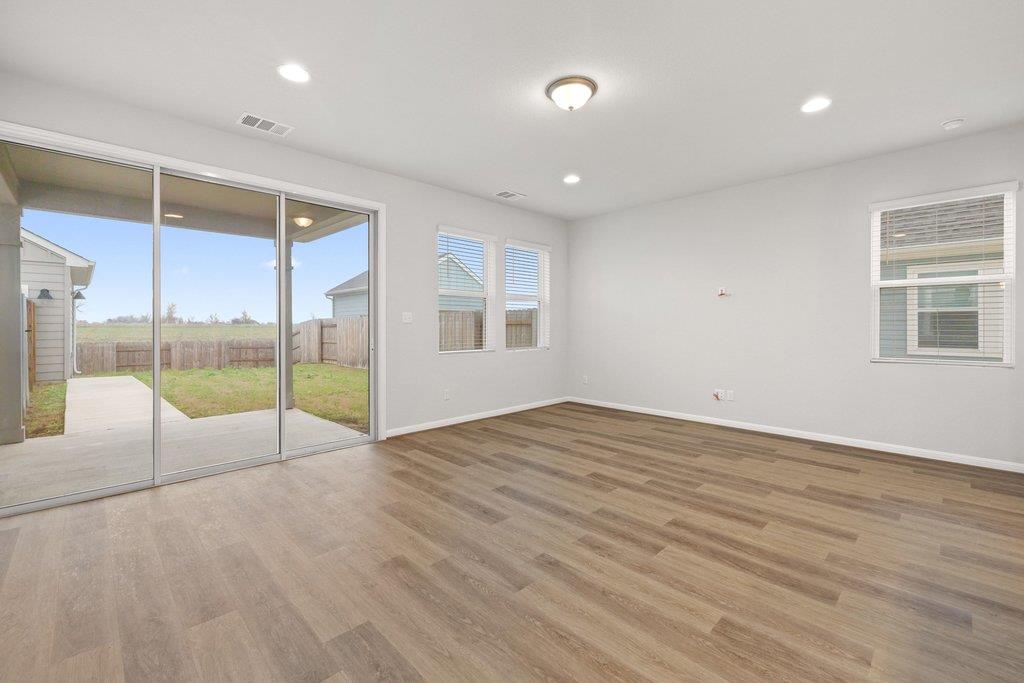 Vacant living area with wood-look floors and sliding glass doors to a covered patio.