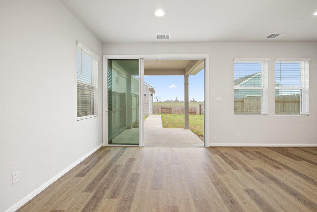 Vacant room with wood-look flooring and sliding glass doors opening to a covered patio.