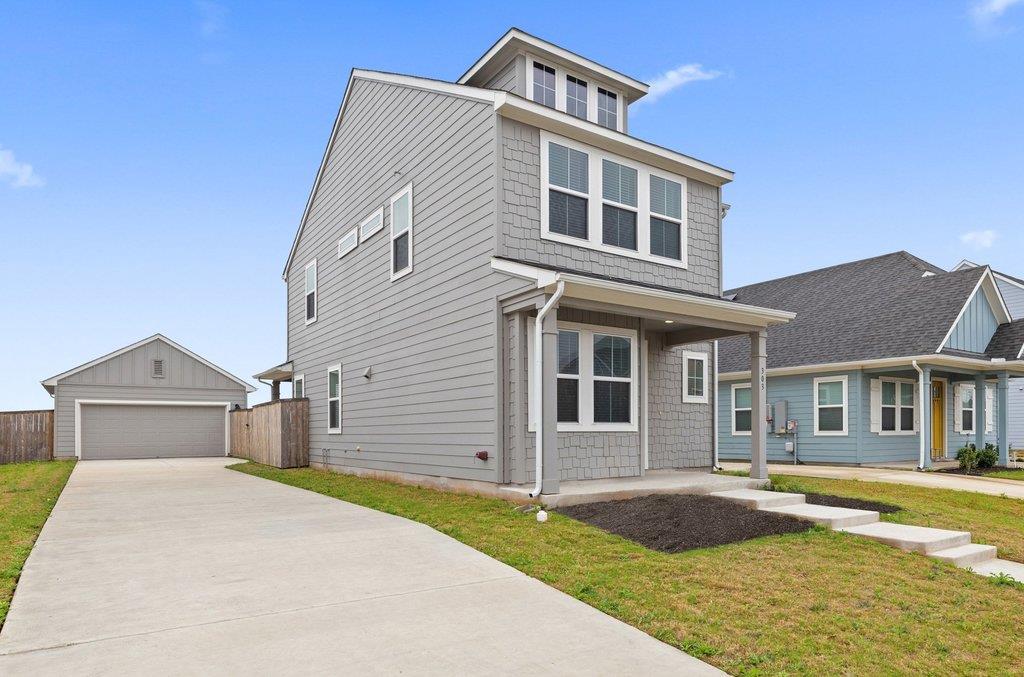 Two-story gray house with white trim, a covered entry, and a driveway to a detached garage.