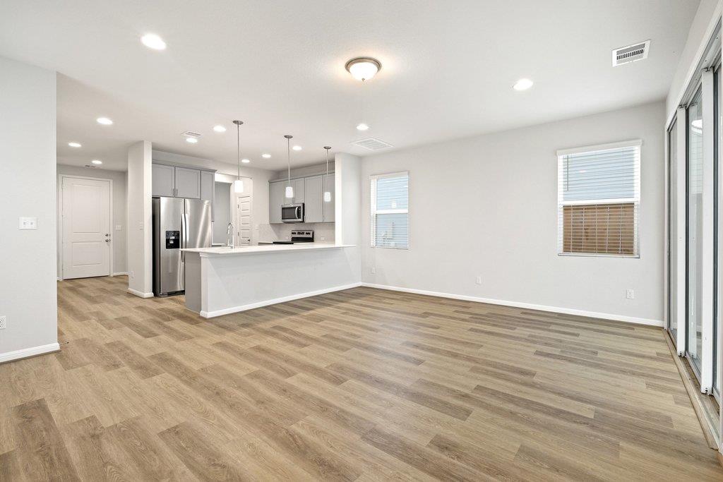 Open-plan living area and kitchen with gray cabinets, stainless appliances, and wood-look floors.