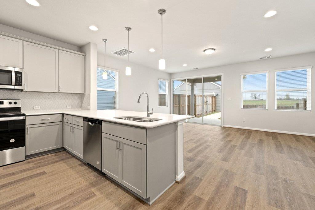 Open-plan kitchen with a large island, stainless steel appliances, and sliding glass doors to a fenced patio.