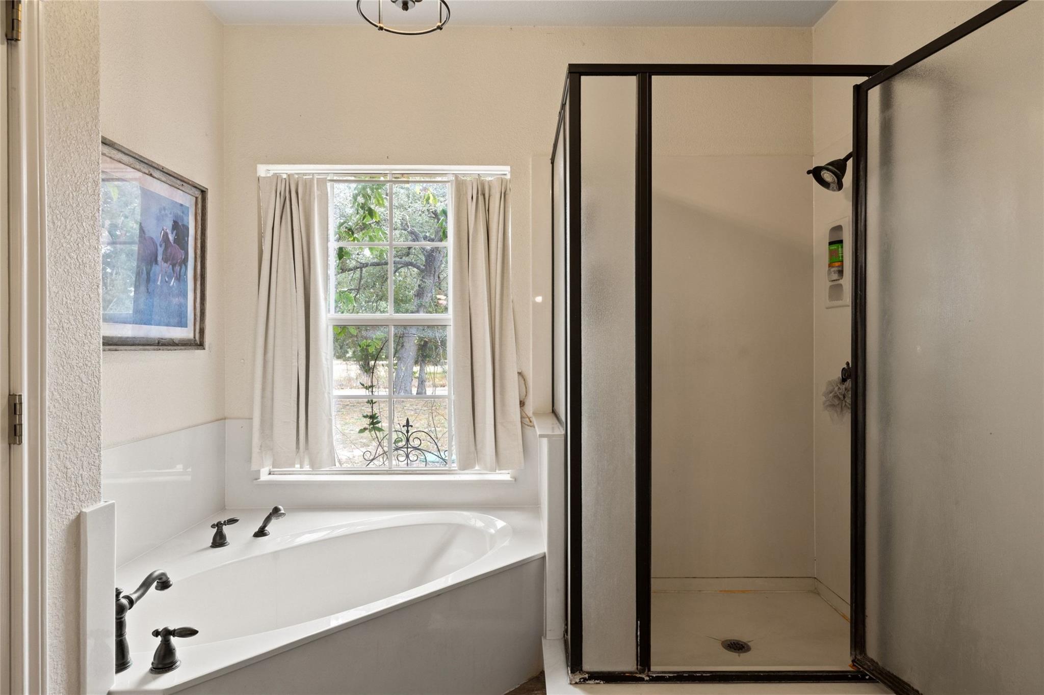 Bathroom with a built-in tub beneath a window and a separate glass-enclosed shower.