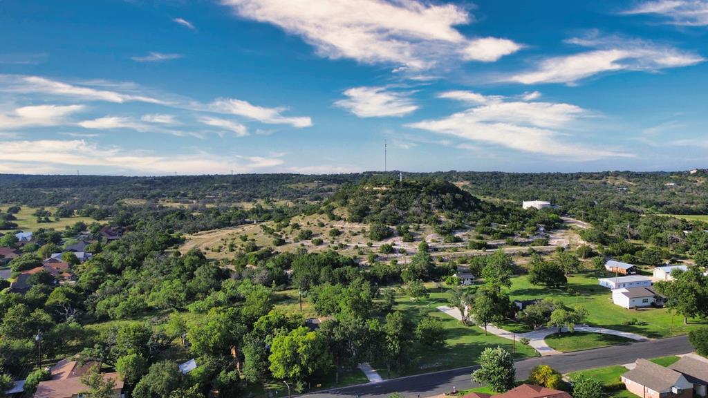 Aerial view of rolling green hills and scattered homes near Cross Mountain, with a road in the foreground.