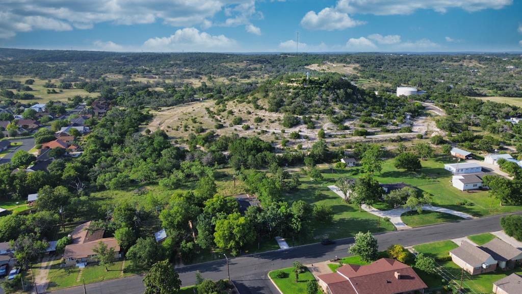 Aerial view of a rocky, tree-covered hill amid Fredericksburg homes and open land.