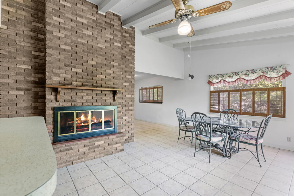 Dining area with a glass-top table beside a large brick fireplace.