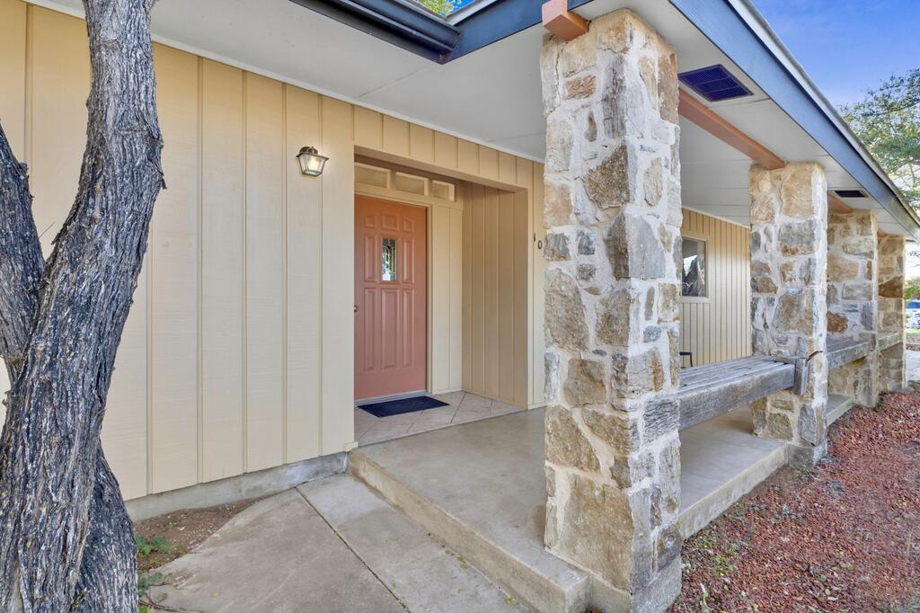 Home entrance with a coral door, stone columns, and a covered porch.