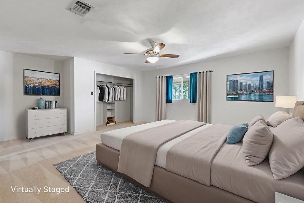 Virtually staged bedroom with a large bed, open closet, and ceiling fan.