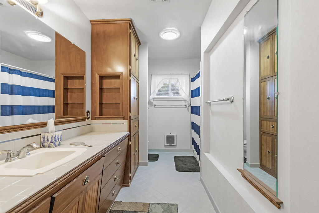 Bathroom with a long wood vanity, built-in cabinets, and a blue-and-white striped shower curtain.