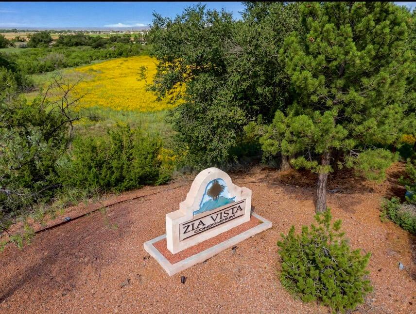 Zia Vista Condominium entrance sign amid trees and a yellow wildflower field.