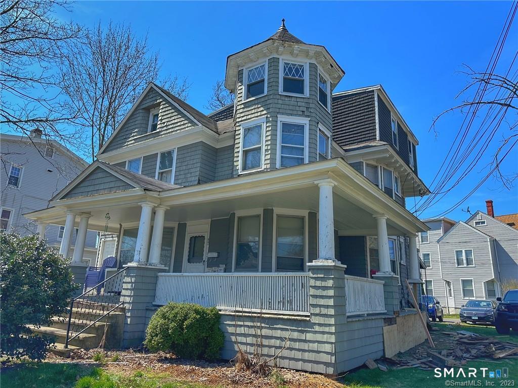 Gray Victorian-style house with a wraparound porch and prominent corner turret.