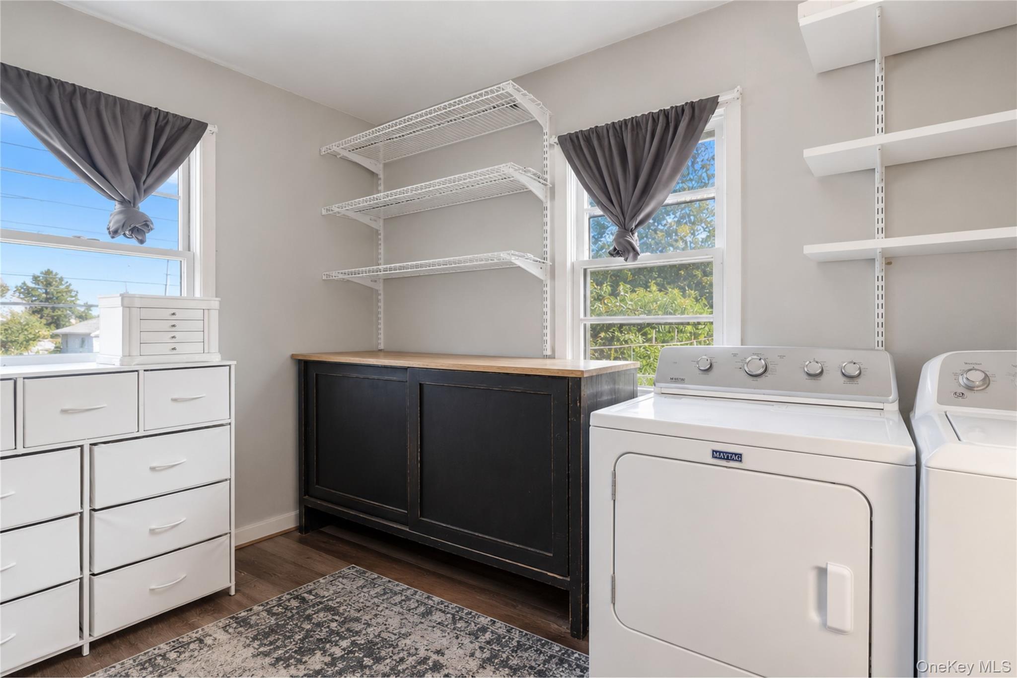 Laundry room with washer and dryer, black work counter, wire shelves, and white drawer storage.
