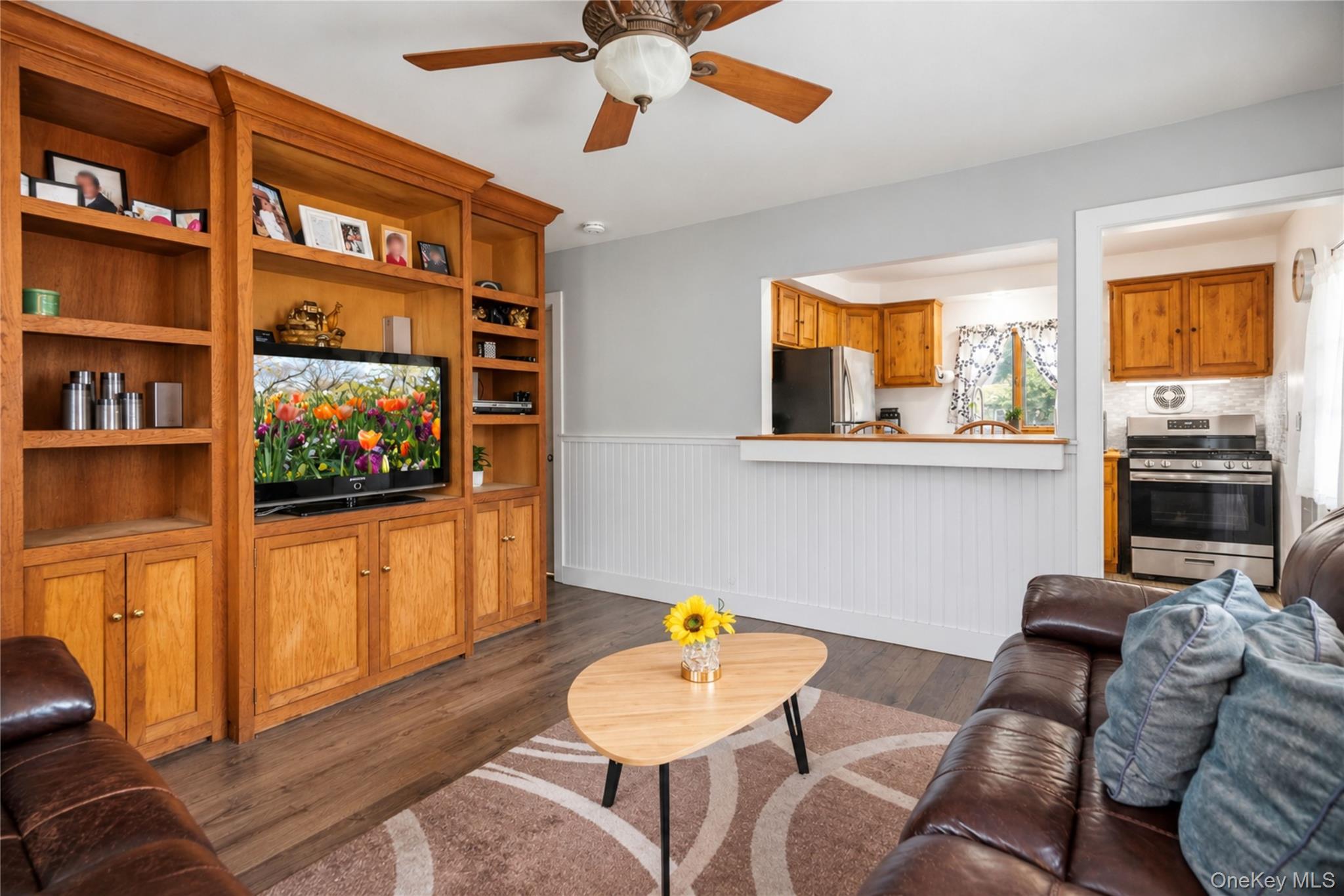 Living room with built-in wooden shelving, leather sofas, and a pass-through to the kitchen.