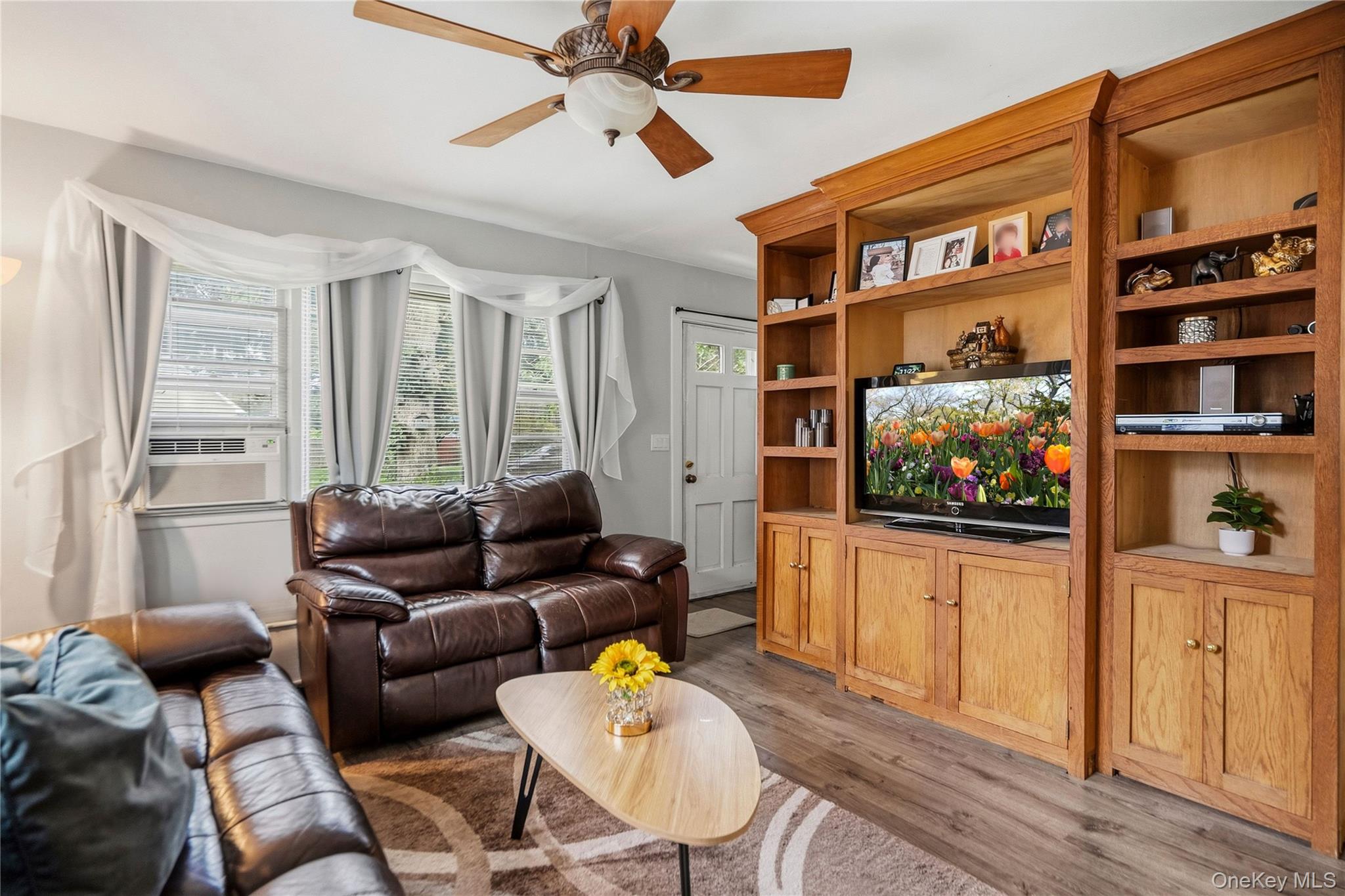 Furnished living room with leather sofas and a large built-in wooden entertainment center.