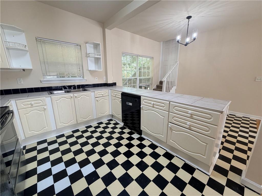 Kitchen with white paneled cabinets, checkerboard flooring, and a peninsula with a built-in dishwasher.