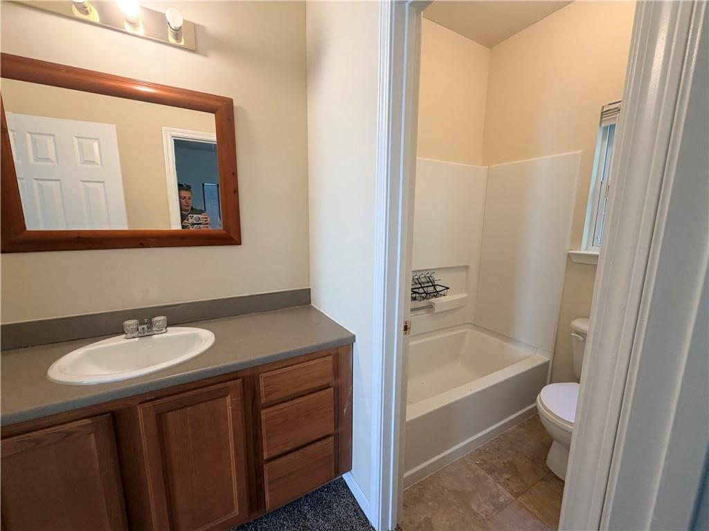 Bathroom with a wooden vanity, oval sink, bathtub, and white surround panels.
