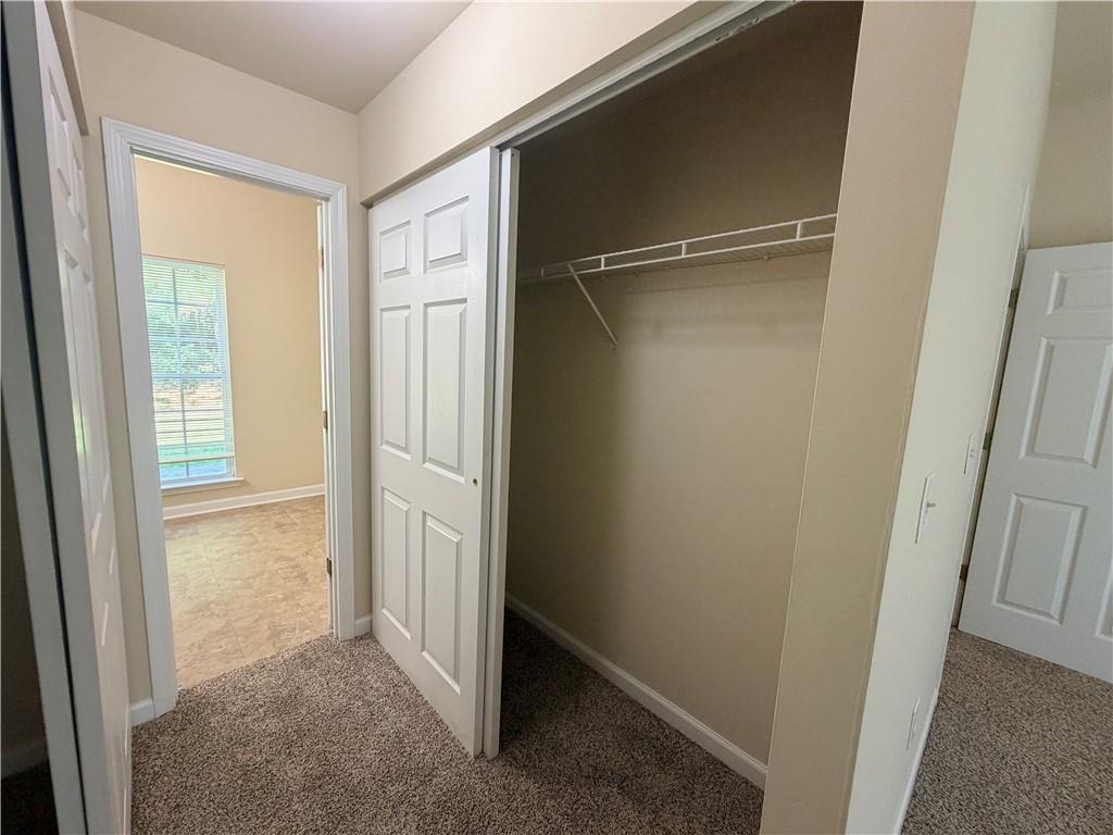Open empty closet with a white wire shelf beside a doorway to a bright room.