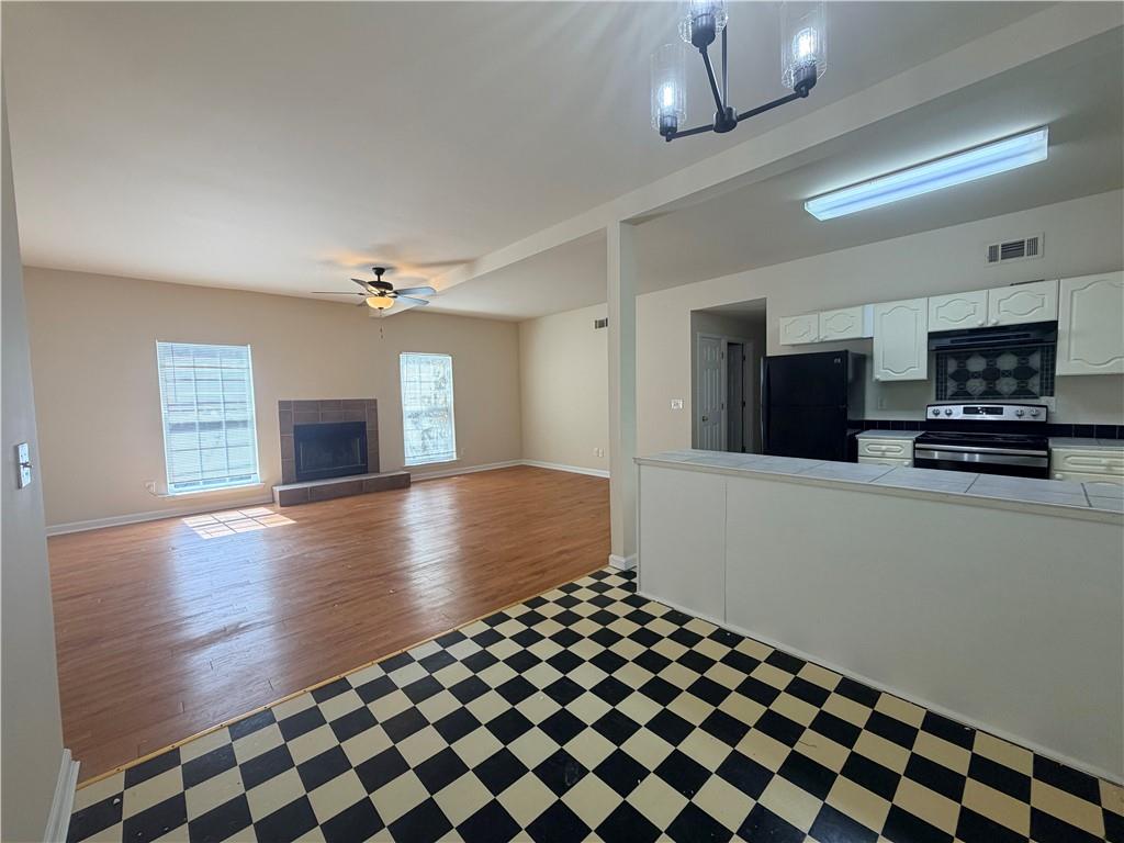 Open kitchen and living room with checkerboard tile, wood flooring, and a fireplace.