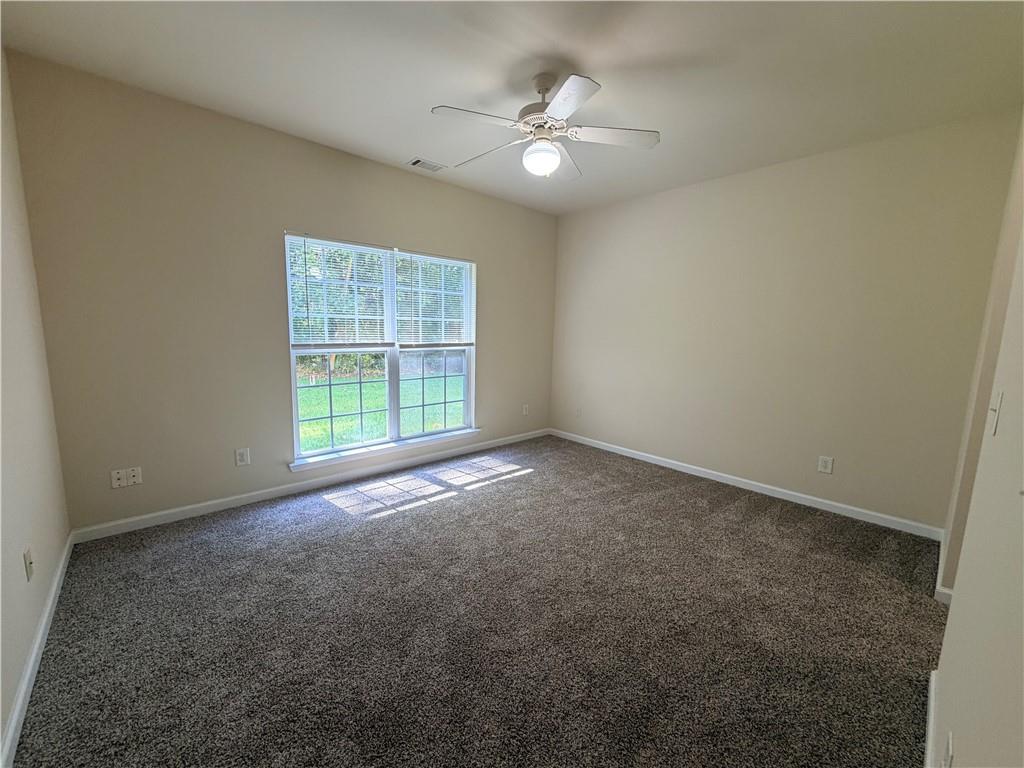 Empty carpeted bedroom with a double window and ceiling fan