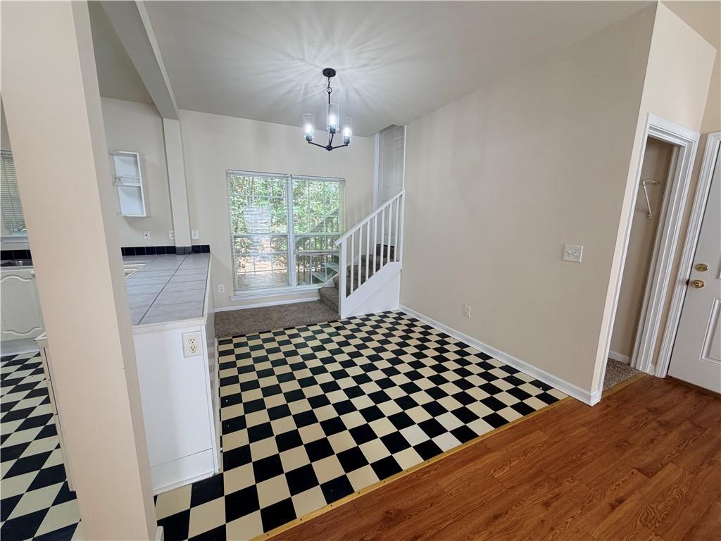 Unfurnished entry area with checkerboard tile, a staircase, and a large window.
